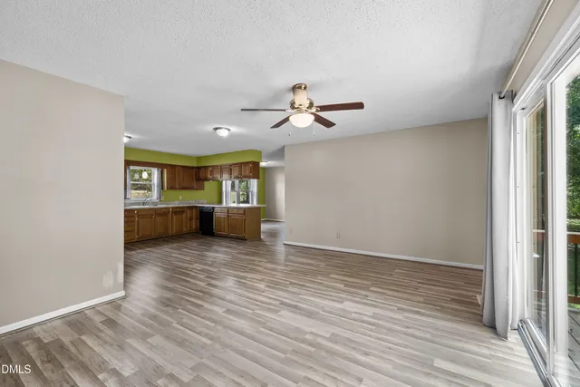 a view of a big room with wooden floor a ceiling fan and windows