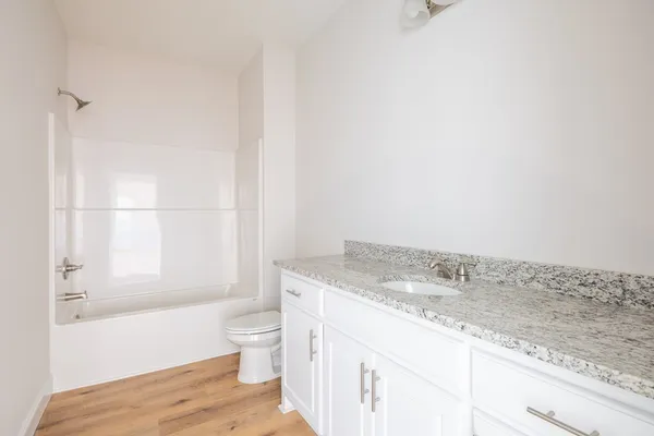 a bathroom with a granite countertop sink a toilet and shower