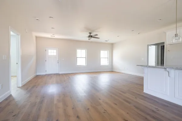 an empty room with wooden floor and windows