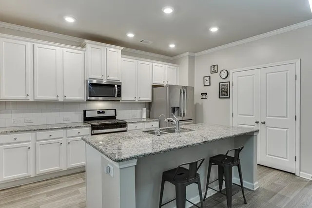 a kitchen with a refrigerator a microwave a stove and white cabinets with wooden floor