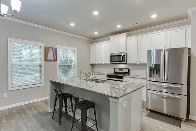 a kitchen with stainless steel appliances granite countertop a table chairs sink and microwave