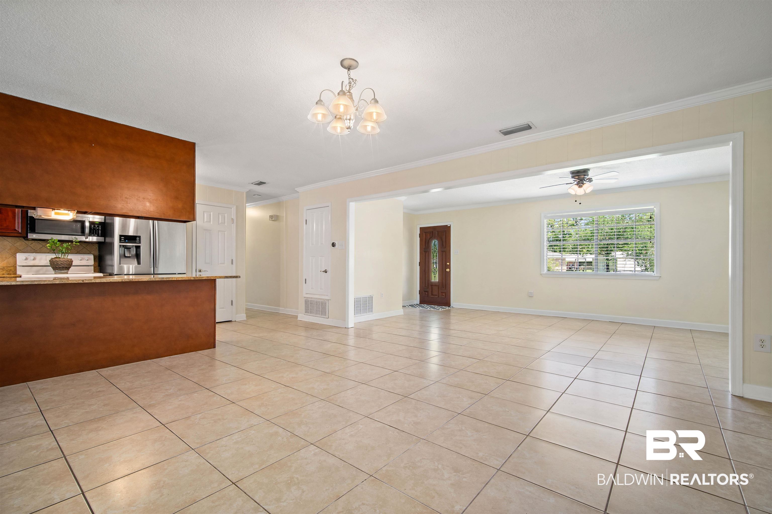1325 Pawnee Circle Saraland, AL 36571 - Photo 7 of 26 Unfurnished living room with crown molding, light tile patterned floors, and a chandelier
