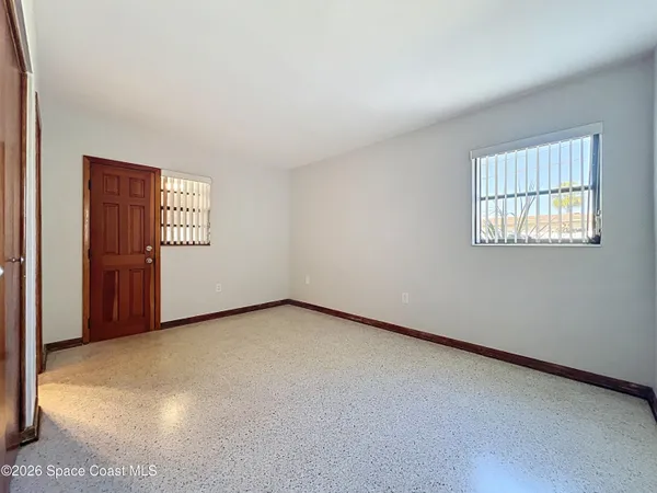 a view of an empty room with a window and a kitchen