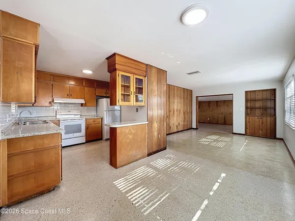 a view of a kitchen with a sink and dishwasher a refrigerator with white cabinets