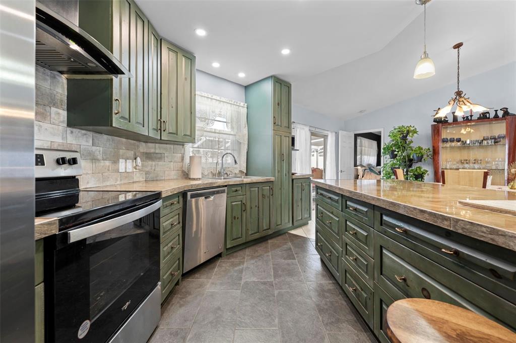 4307 Goldcoast Avenue Spring Hill, FL 34609 - Photo 24 of 53 a kitchen with stainless steel appliances kitchen island granite countertop a sink a stove and a wooden cabinets