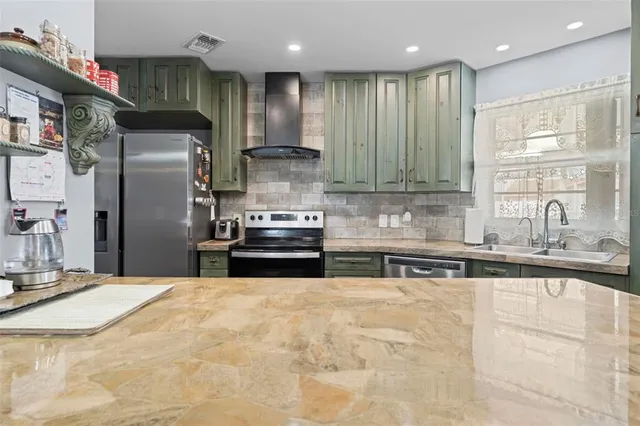 a kitchen with stainless steel appliances granite countertop a sink a stove and a refrigerator