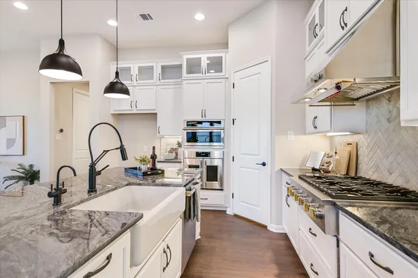 a kitchen with granite countertop a sink stainless steel appliances and cabinets