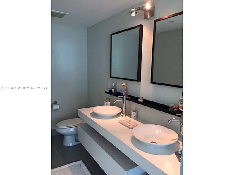92 Southwest 3rd Street, Unit 2911 Miami, FL 33130 - Photo 7 of 16 a bathroom with a granite countertop sink and a mirror