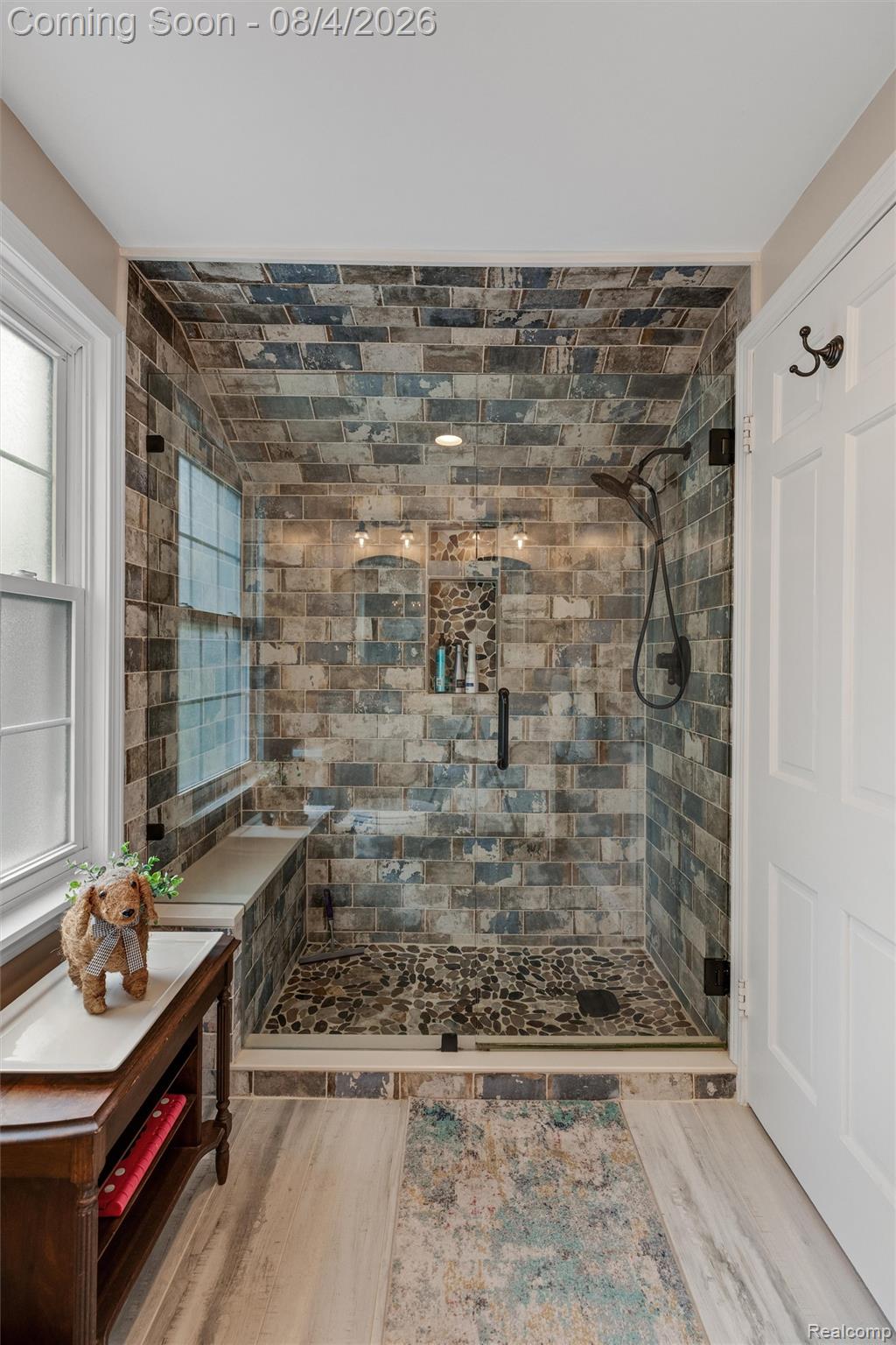 1729 Broadstone Road Grosse Pointe, MI 48236 - Photo 24 of 39 Walk-in shower with varied tone subway tile, river rock shower floor, built-in bench, integrated wall niche storage, and matte black fixtures