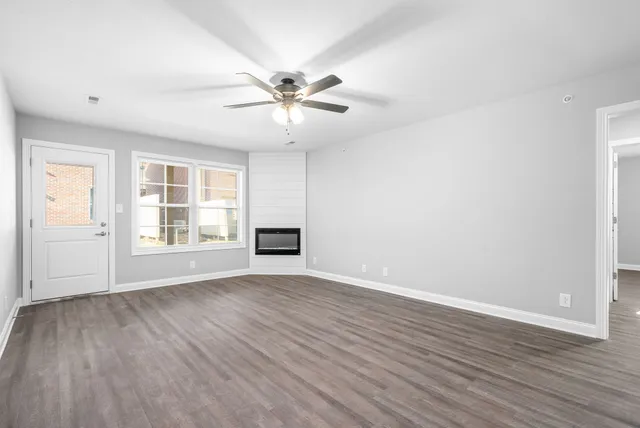 an empty room with wooden floor fan and windows