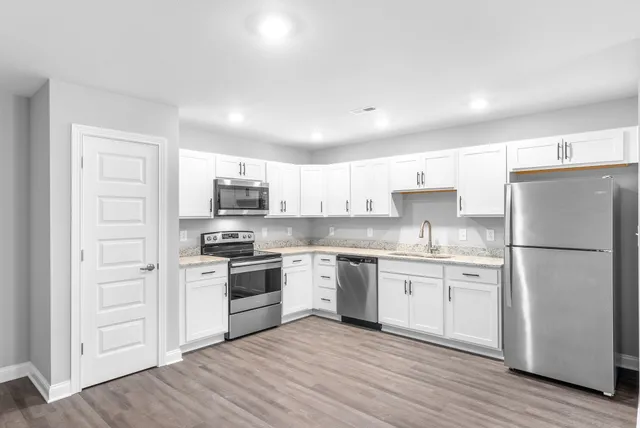 a kitchen with white cabinets stainless steel appliances and a refrigerator