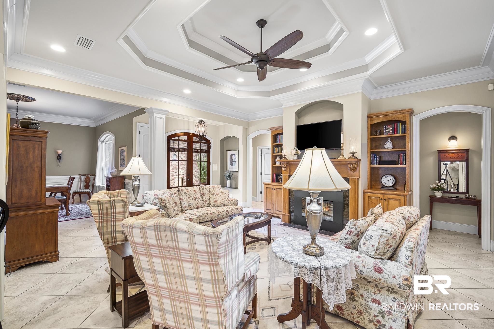 7090 Carson Lane Daphne, AL 36527 - Photo 5 of 37 Living room featuring light tile patterned floors, a tray ceiling, and ornamental molding