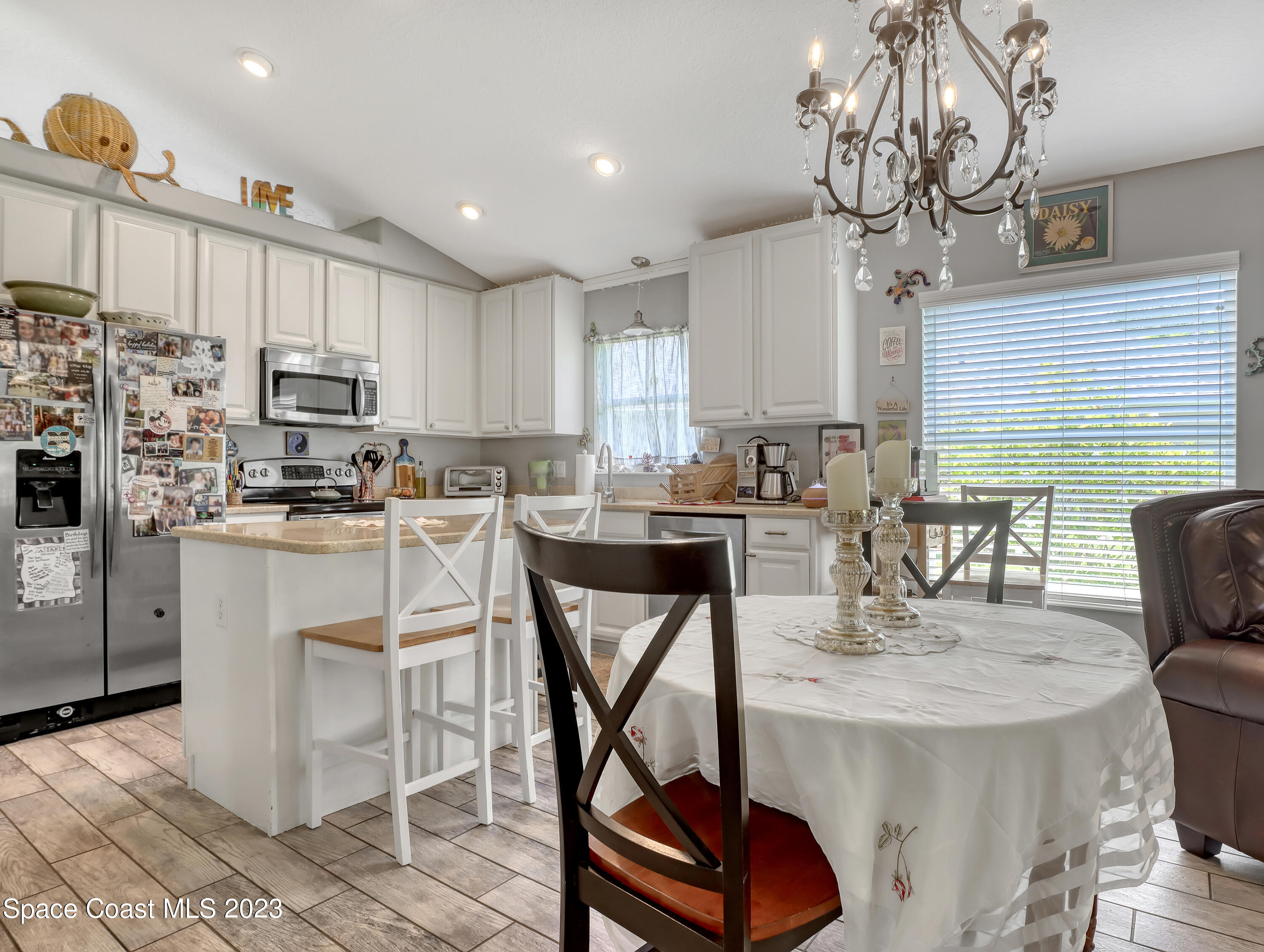 3625 Fodder Drive Rockledge, FL 32955 - Photo 13 of 47 a kitchen with stainless steel appliances kitchen island granite countertop a refrigerator a stove a sink a dining table and chairs with wooden floor