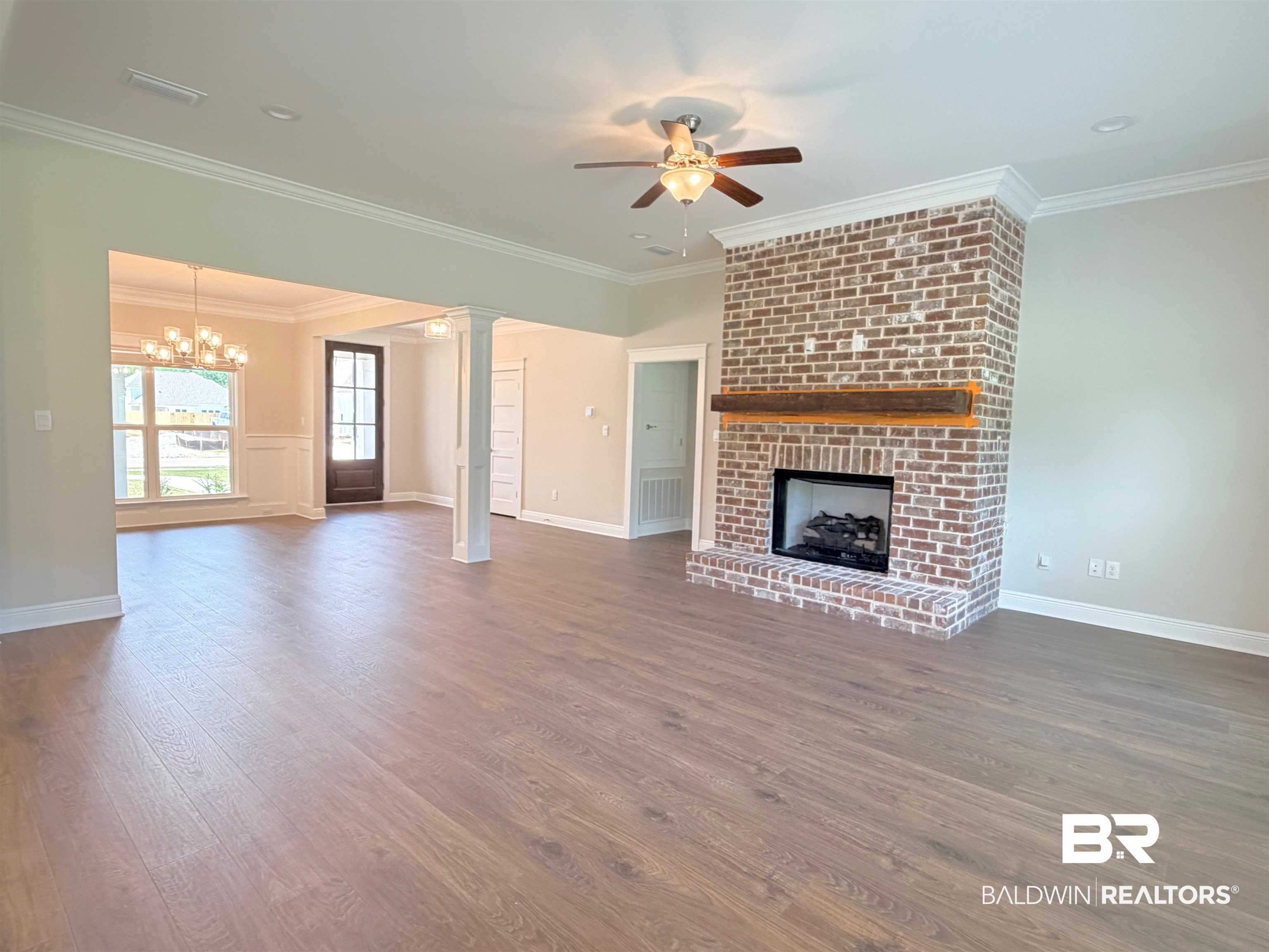 318 Morning Mist Way Fairhope, AL 36532 - Photo 2 of 20 Spacious living area featuring wood-finish flooring, a brick fireplace with a wood mantle, crown molding, and a ceiling fan
