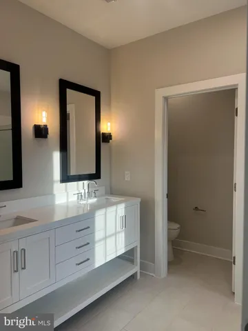 a bathroom with a double vanity sink a toilet and a mirror