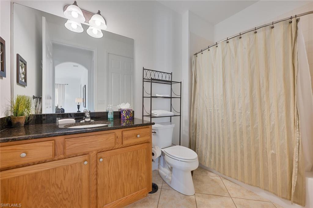 8945 Malibu Street, Unit 204 Naples, FL 34113 - Photo 12 of 21 a bathroom with a toilet a sink a mirror and a shower