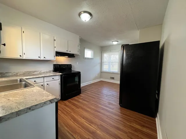 a kitchen with granite countertop white cabinets and black appliances