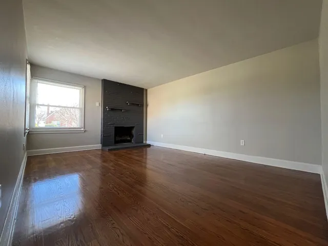 an empty room with wooden floor and fireplace