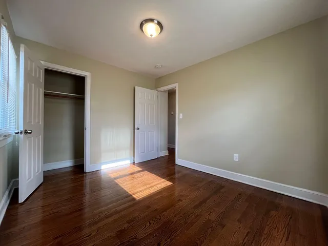 an empty room with wooden floor & closet area