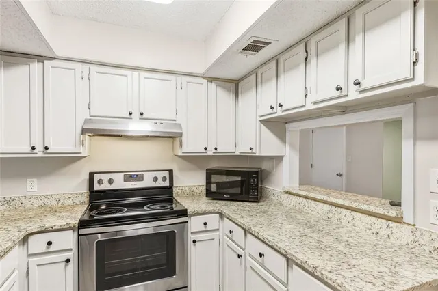 a kitchen with granite countertop white cabinets and stainless steel appliances