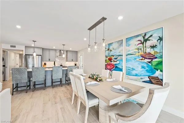 a view of a dining room and livingroom with furniture wooden floor a rug a painting and a chandelier