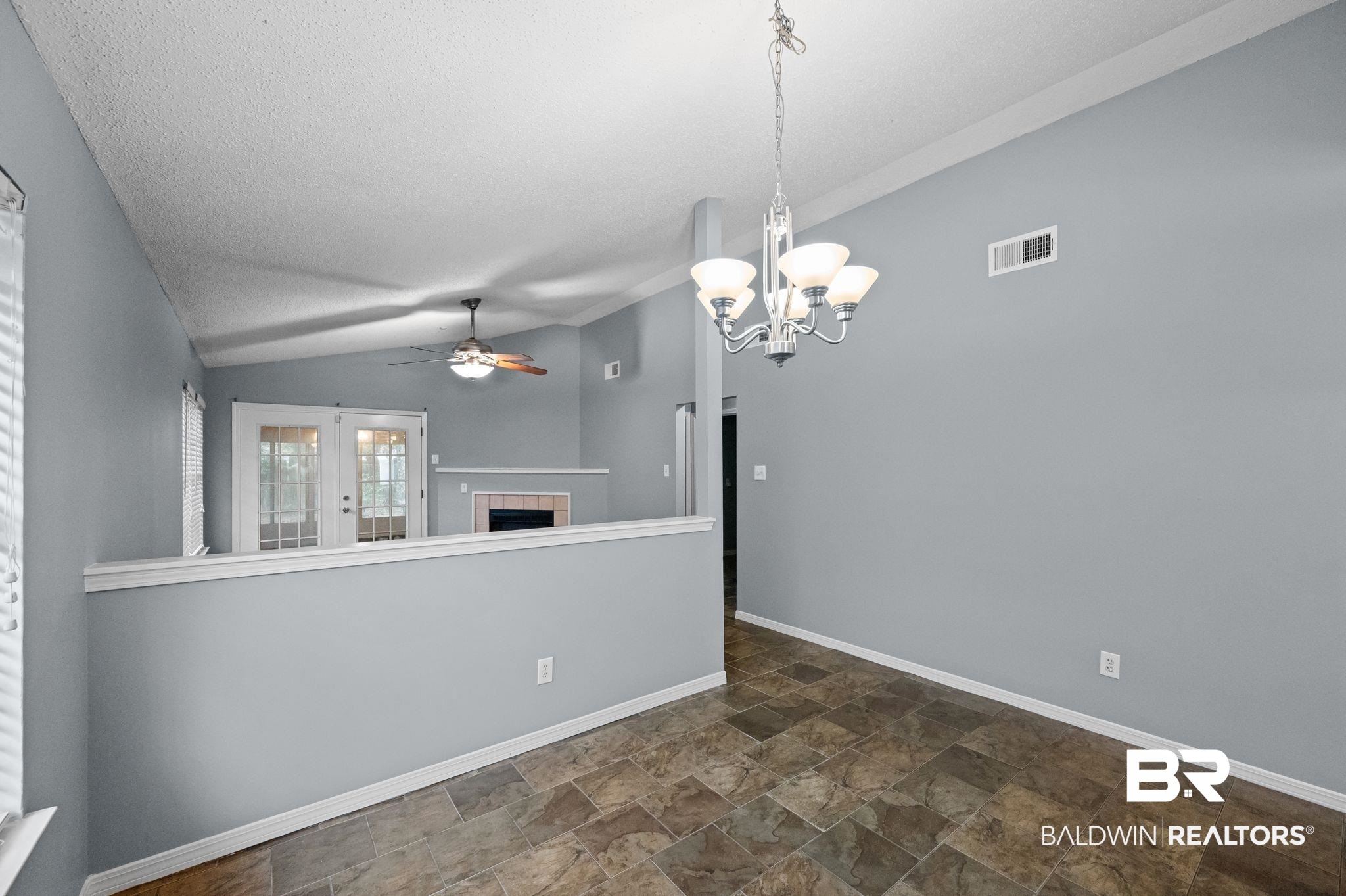3744 Pepper Ridge Drive Mobile, AL 36693 - Photo 5 of 29 Empty room featuring stone finish flooring, vaulted ceiling, a chandelier, a fireplace, and a ceiling fan