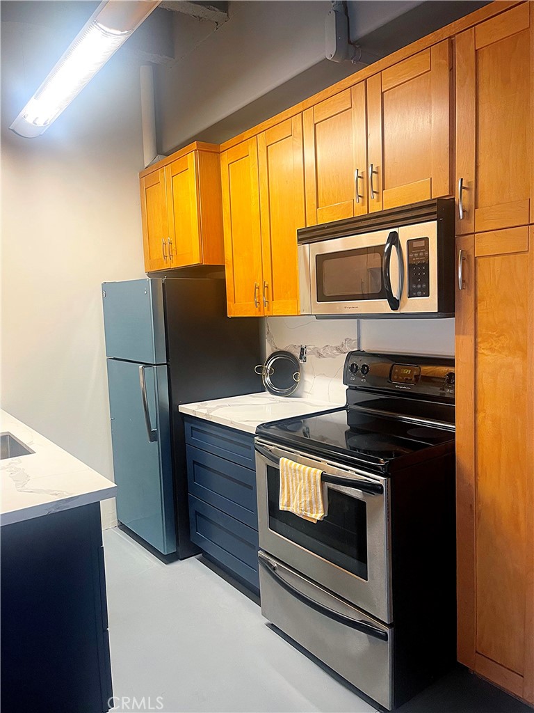 312 West 5th Street, Unit 1003 Los Angeles, CA 90013 - Photo 5 of 20 a kitchen with stainless steel appliances wooden cabinets and a stove top oven