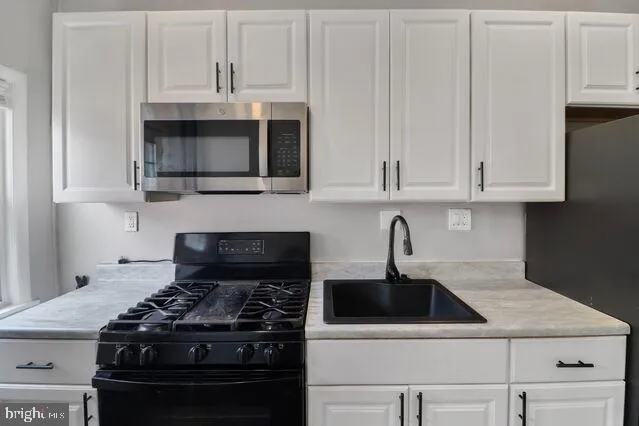 a kitchen with granite countertop white cabinets and stainless steel appliances