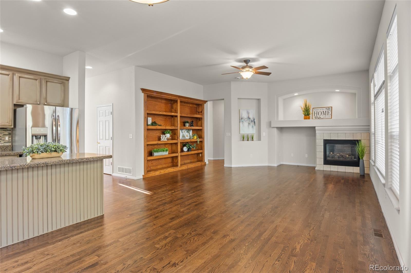 20800 Omaha Avenue Parker, CO 80138 - Photo 11 of 38 an empty room with wooden floor fireplace and windows