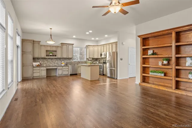 a large kitchen with stainless steel appliances granite countertop a stove oven a refrigerator and white cabinets with wooden floor