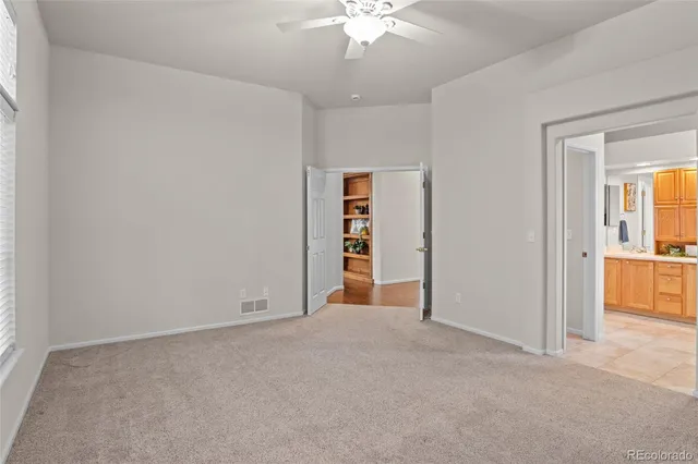 an empty room with closet and a chandelier fan