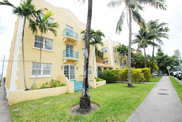 a front view of a house with a yard and palm trees