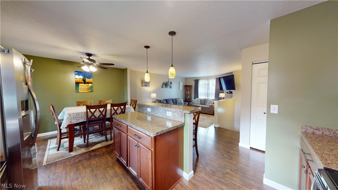 3805 Townline Road Madison, OH 44057 - Photo 12 of 38 Kitchen featuring stainless steel fridge with ice dispenser, a breakfast bar, dark wood-type flooring, light stone counters, and ceiling fan