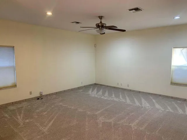 an empty room with a ceiling fan and window