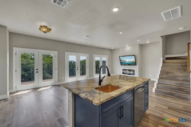 a kitchen with granite countertop a sink and wooden floor