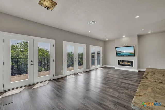a view of an empty room with wooden floor and windows