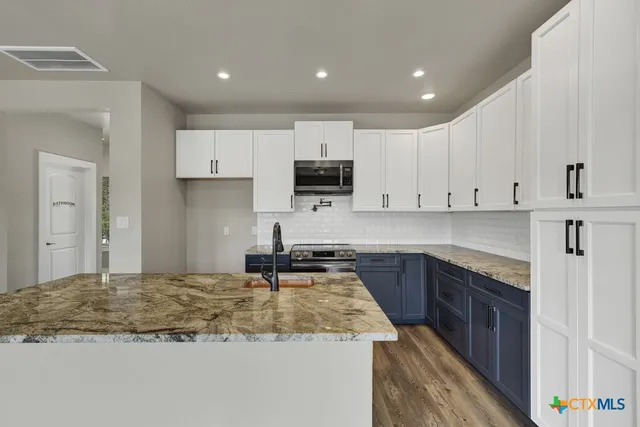 a kitchen with kitchen island granite countertop a sink stove and cabinets
