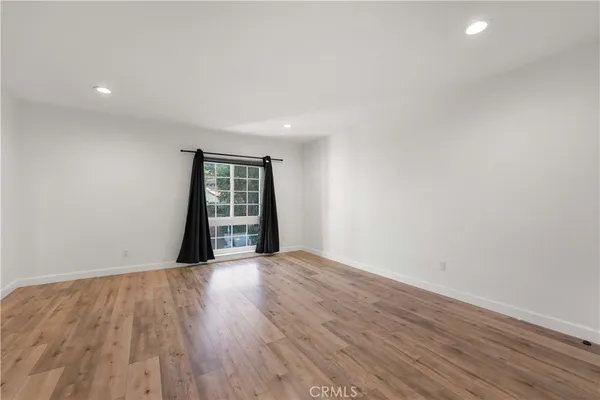 a view of an empty room with wooden floor and closet