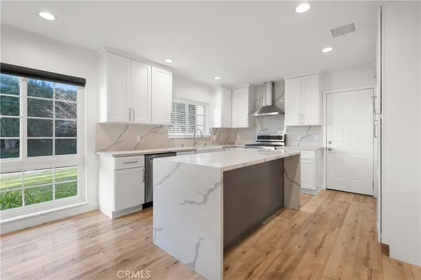 a kitchen with kitchen island granite countertop a sink cabinets and wooden floor