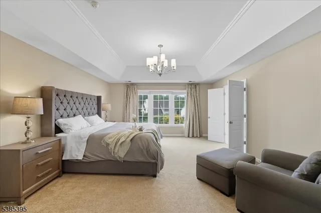 a spacious bedroom with a bed a couch and a chandelier