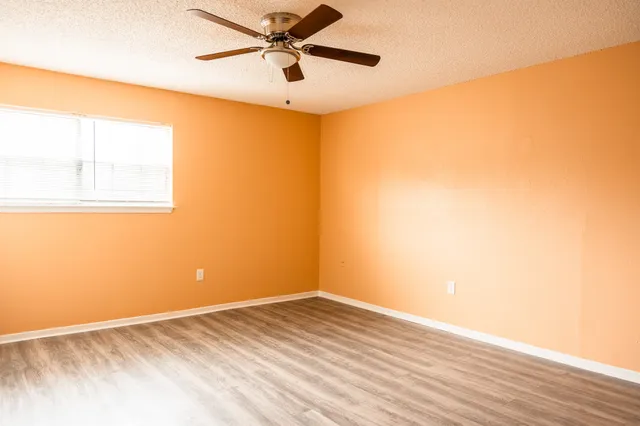 a view of a big room with wooden floor and a ceiling fan