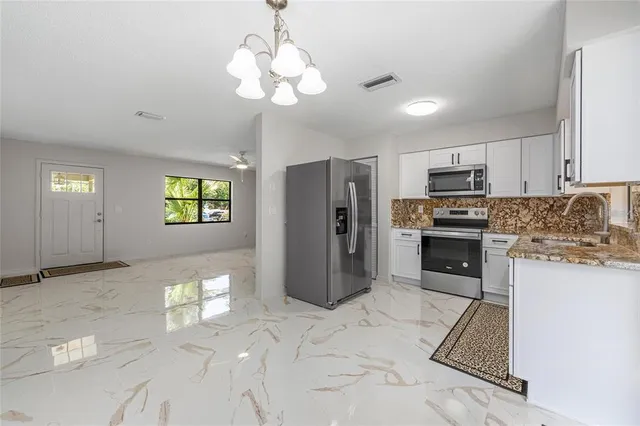 a kitchen with stainless steel appliances granite countertop a refrigerator a stove a sink a stove a dining table and chairs with wooden floor