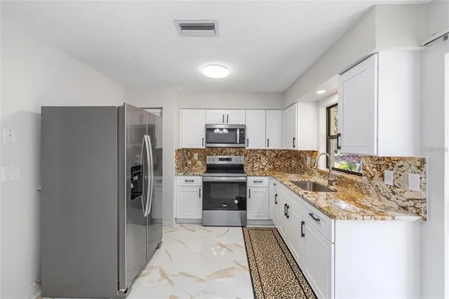 a kitchen with stainless steel appliances granite countertop a refrigerator stove and sink