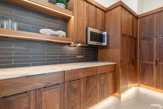 3607 South Cypress Pt Road Hurricane, UT 84737 - Photo 25 of 59 Kitchen featuring wood finish cabinetry, backsplash, open shelves, stainless steel microwave, and light stone counters