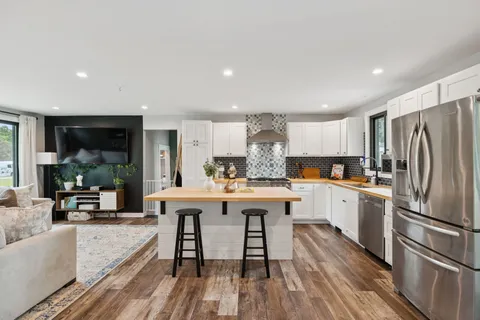 a kitchen with stainless steel appliances a dining table chairs refrigerator and sink