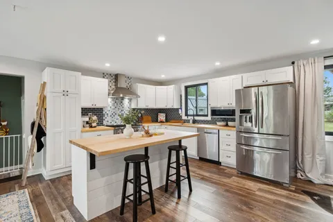 a kitchen with refrigerator and wooden floor