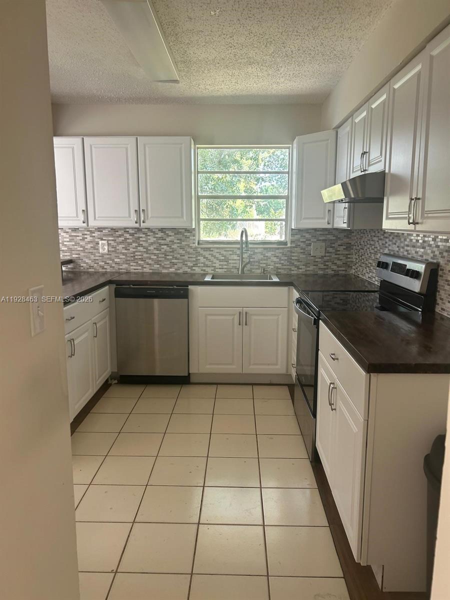 1599 Northeast Cindy Circle, Unit A Palm Bay, FL 32905 - Photo 3 of 13 a kitchen with stainless steel appliances granite countertop a sink and dishwasher a stove top oven with wooden floor
