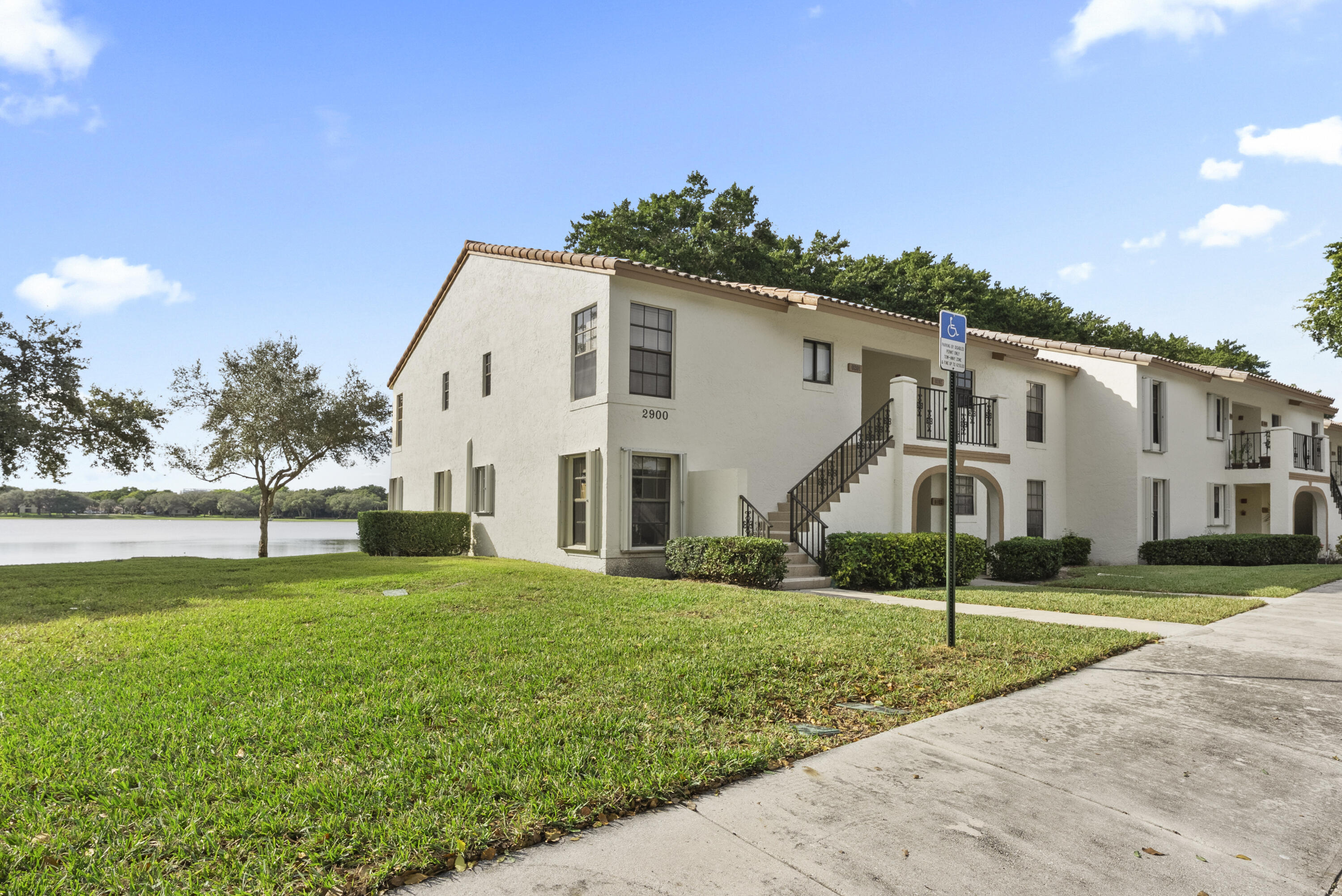 2900 Olivewood Terrace, Unit 2010 Boca Raton, FL 33431 - Photo 21 of 22 a view of a white house in front of a big yard with plants and large trees