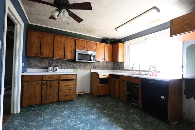 a kitchen with stainless steel appliances granite countertop a sink window and cabinets