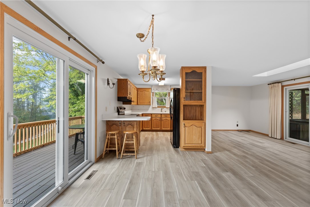 59638 Broadview Road Shadyside, OH 43947 - Photo 7 of 43 Kitchen with light countertops, light wood-style flooring, a breakfast bar area, hanging light fixtures, and a chandelier